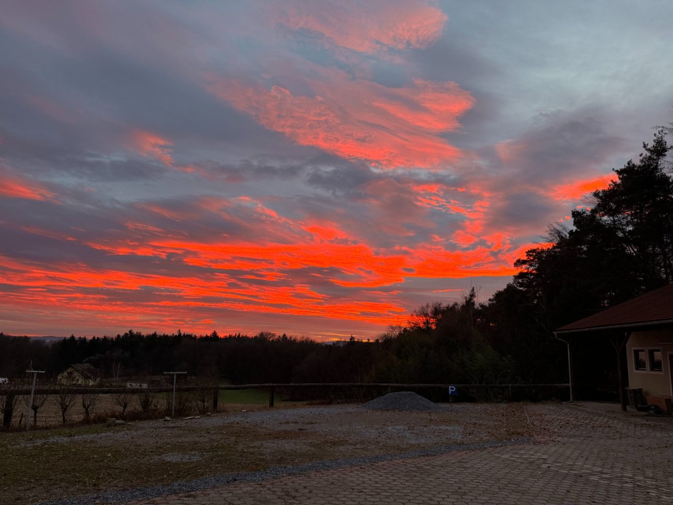 Bunte Abenddämmerung mit roten und orangefarbenen Wolken über der Landschaft.